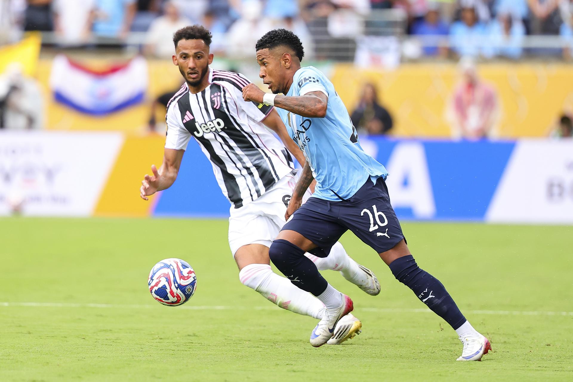 Savinho (d), del Manchester City, avanza con el balón ante la marca de Lloyd Kelly, de Juventus. EFE/EPA/CRISTOBAL HERRERA-ULASHKEVICH