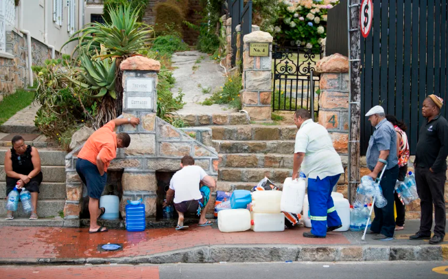 La gente recoge agua potable de tuberías alimentadas por un manantial subterráneo, en Ciudad del Cabo, el 19 de enero de 2018, mientras la ciudad lucha contra su peor sequía en un siglo. Rodger Bosch/AFP/Getty Images