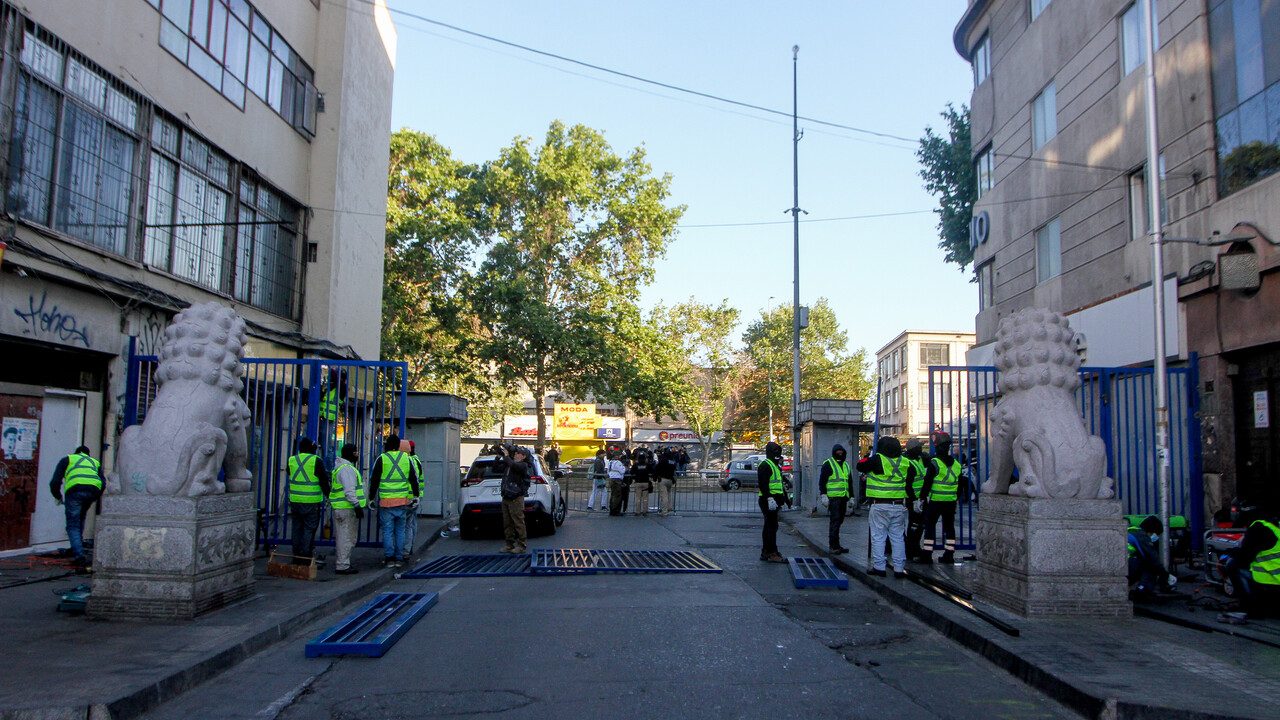 Trabajadores instalan un portón en la entrada de la calle San Alfonso, durante el operativo liderado por la Delegación Presidencial y la municipalidad de Santiago, en conjunto con Carabineros y Seguridad Pública, que se realiza en el barrio Meiggs, como parte de la segunda etapa del plan de despeje de toldos azules/Agencia Uno