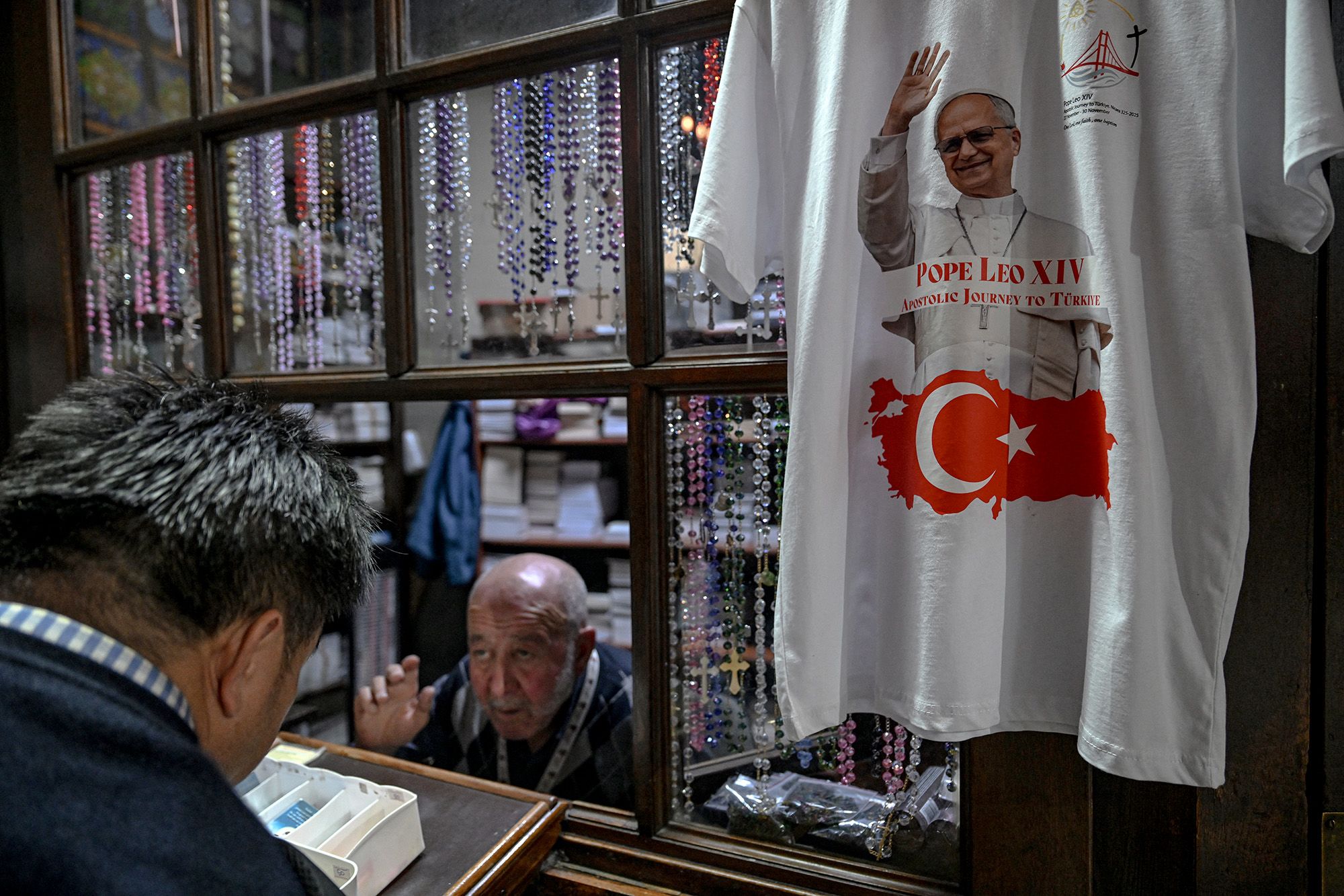 Se venden velas y libros religiosos mientras se exhibe una camiseta con un retrato del Papa León XIV y una bandera turca antes de la visita del Papa a Estambul el lunes. Ozan Kose/AFP/Getty Images